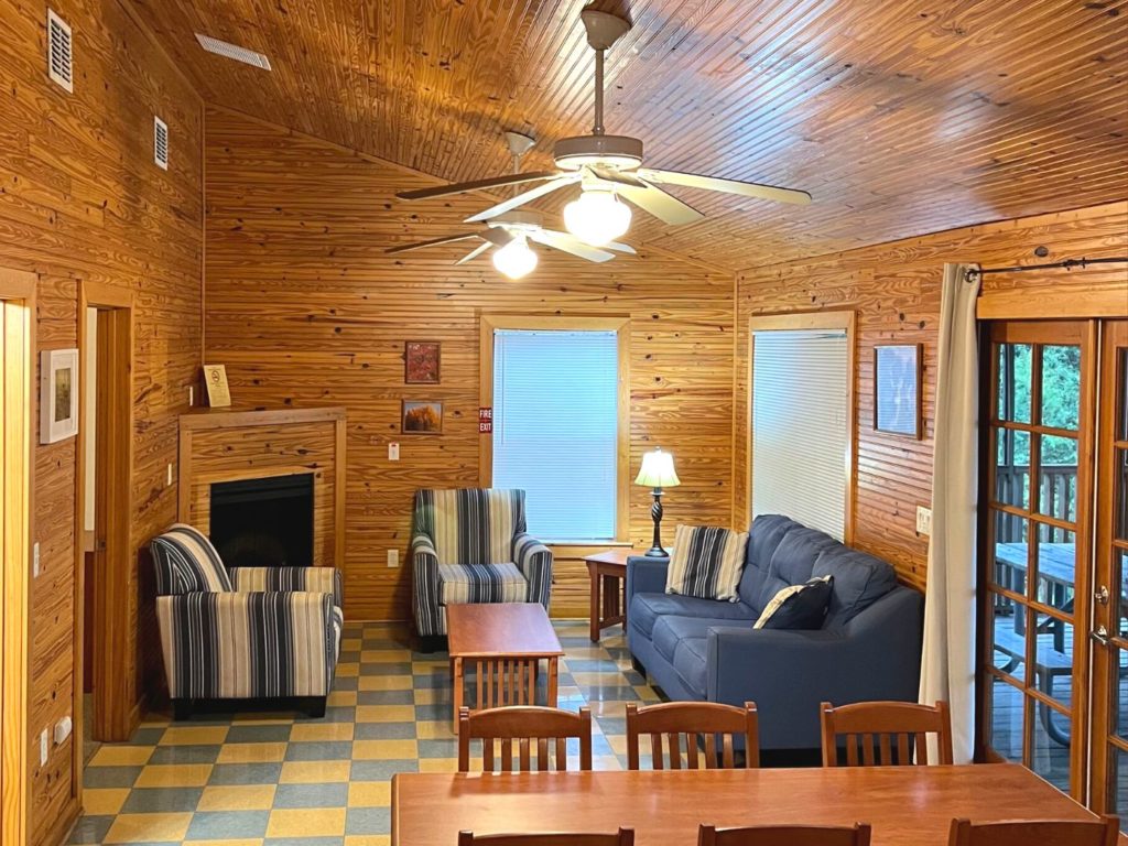 Lake Louisa State Park Cabins - Living room with a couch, two chairs, ceiling fans, and dining table